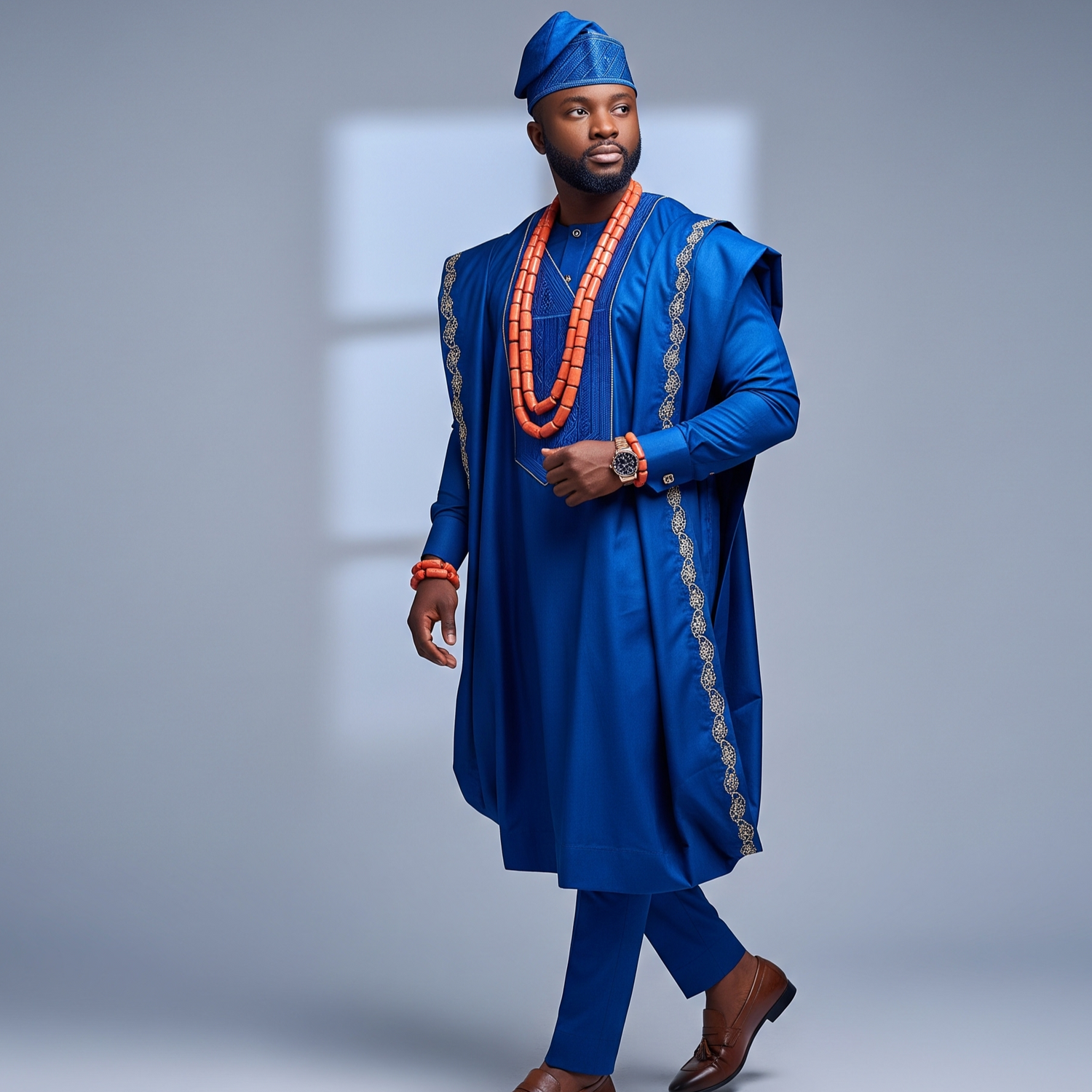 Man wearing a traditional blue outfit with a hat and beads on a gray background