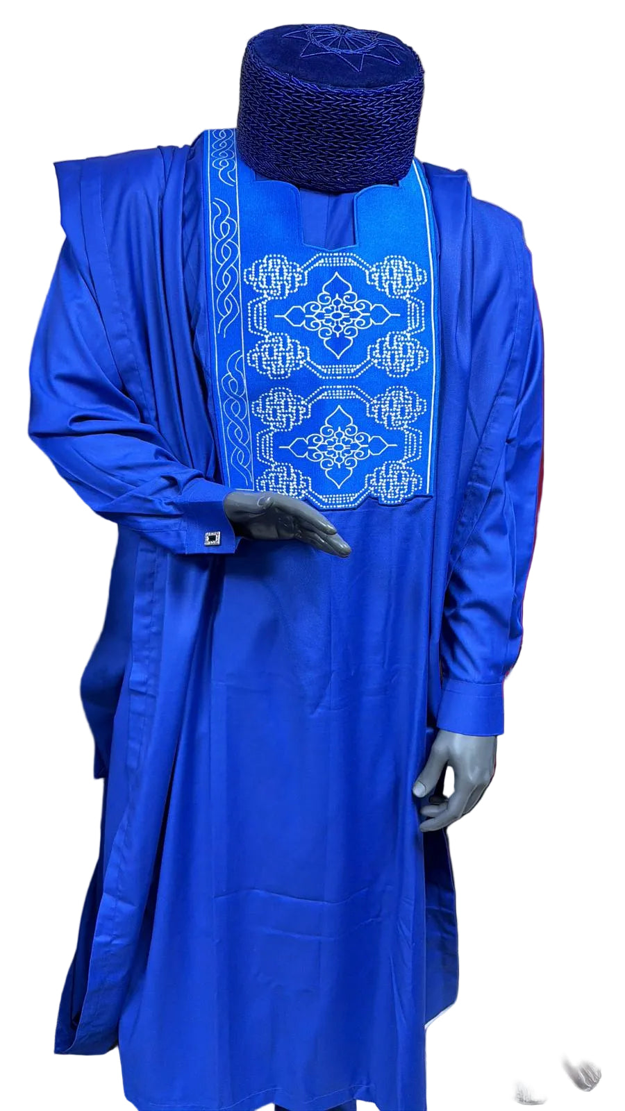 Blue traditional outfit with intricate white embroidery on a mannequin against a beige curtain background.