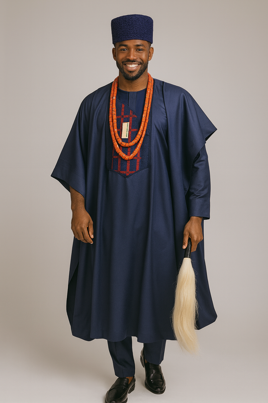 Man wearing a traditional outfit with a navy blue robe and hat, holding a white object, on a plain background.