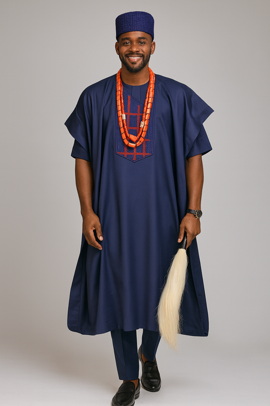 A man wearing a traditional outfit with a blue robe and hat, holding a white object, on a plain background.

